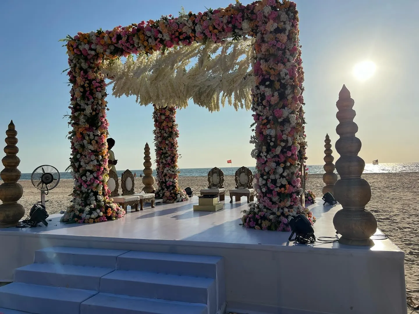 Sunlit beach wedding mandap with floral arch by the Arabian Sea, Imagine Decorators Goa